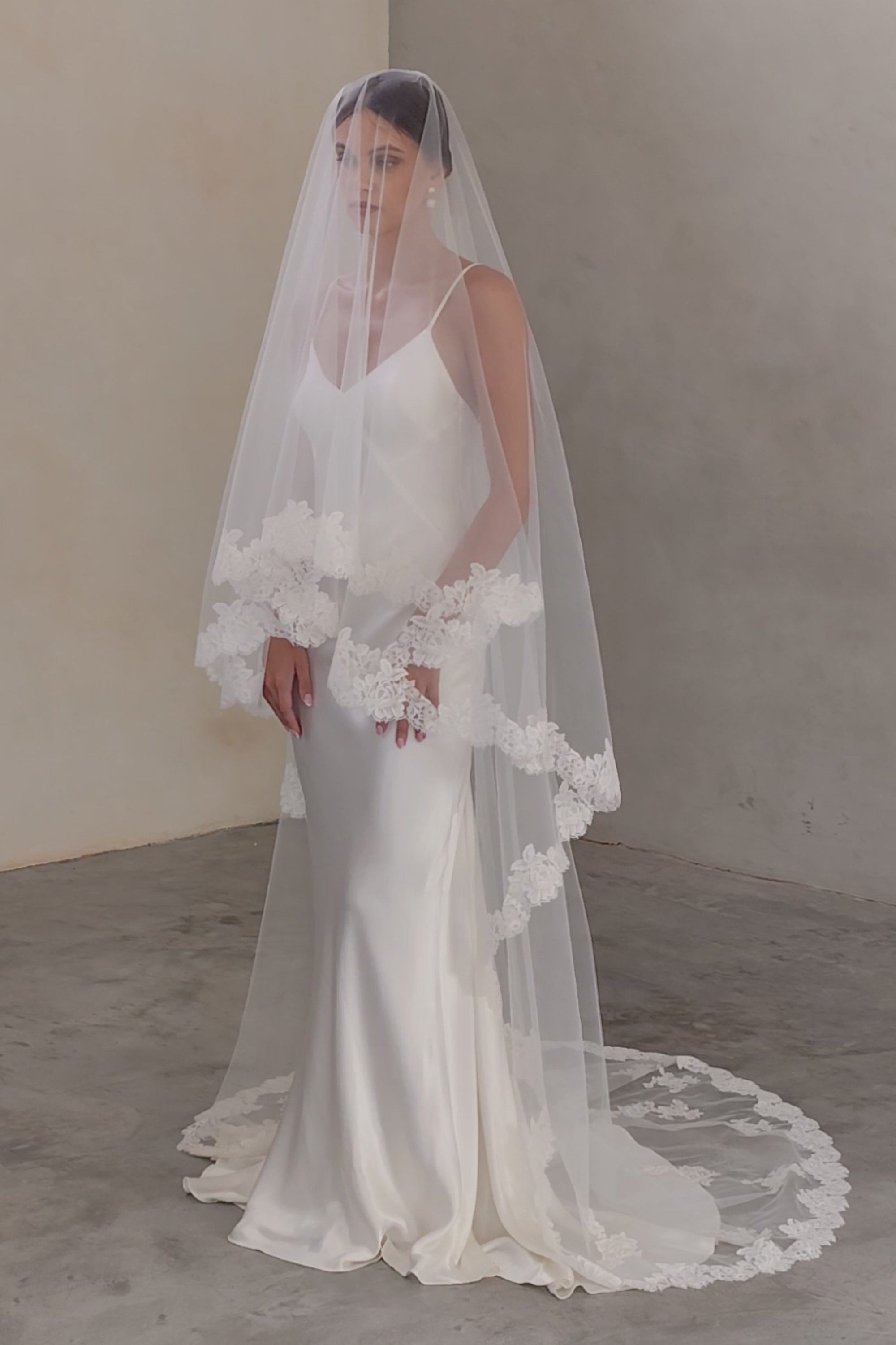 Full length view of bride wearing two-tiered veil (with blusher) featuring floral lace edging and appliques scattered around train