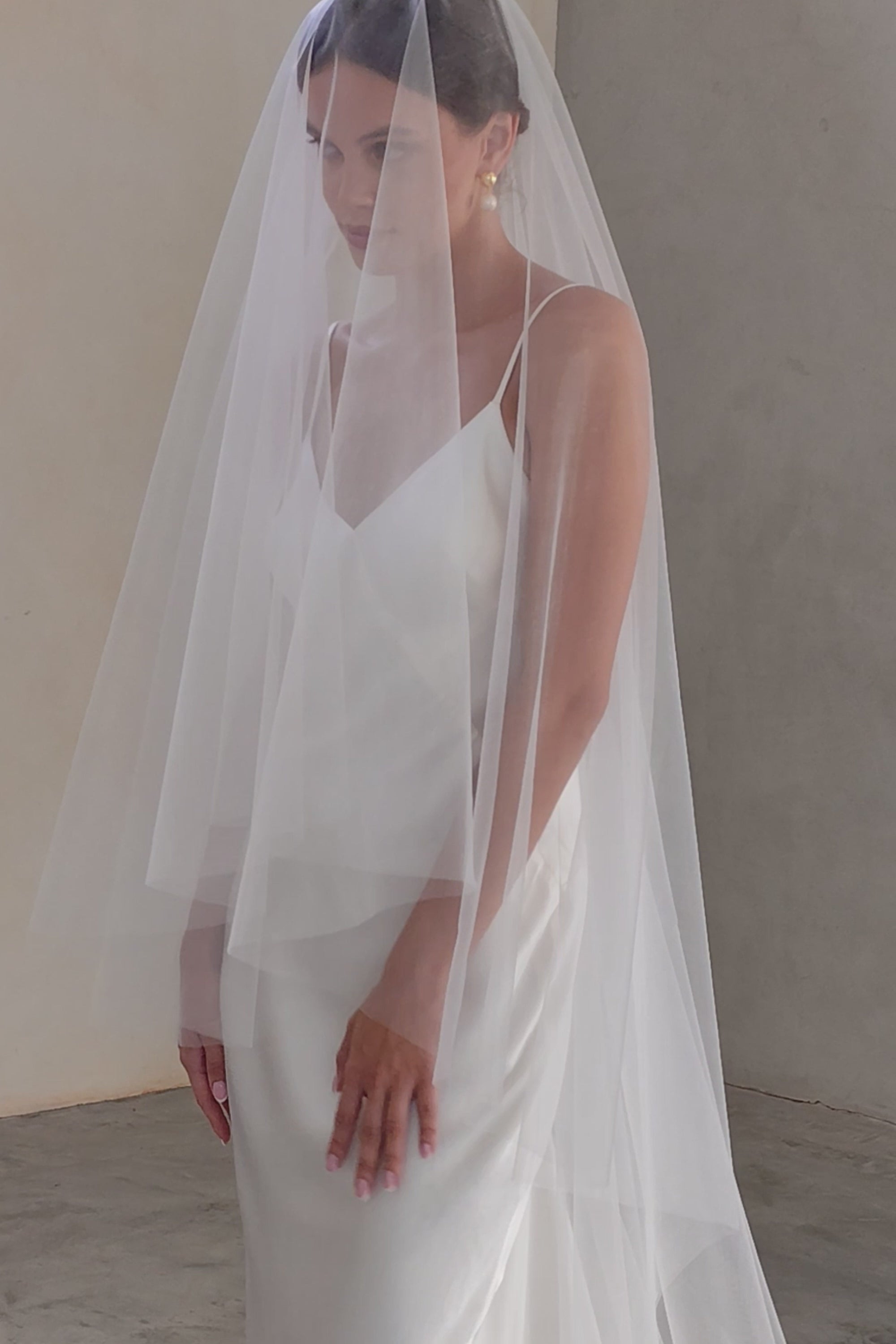 Bride wears two-tier shimmer tulle veil, blusher down