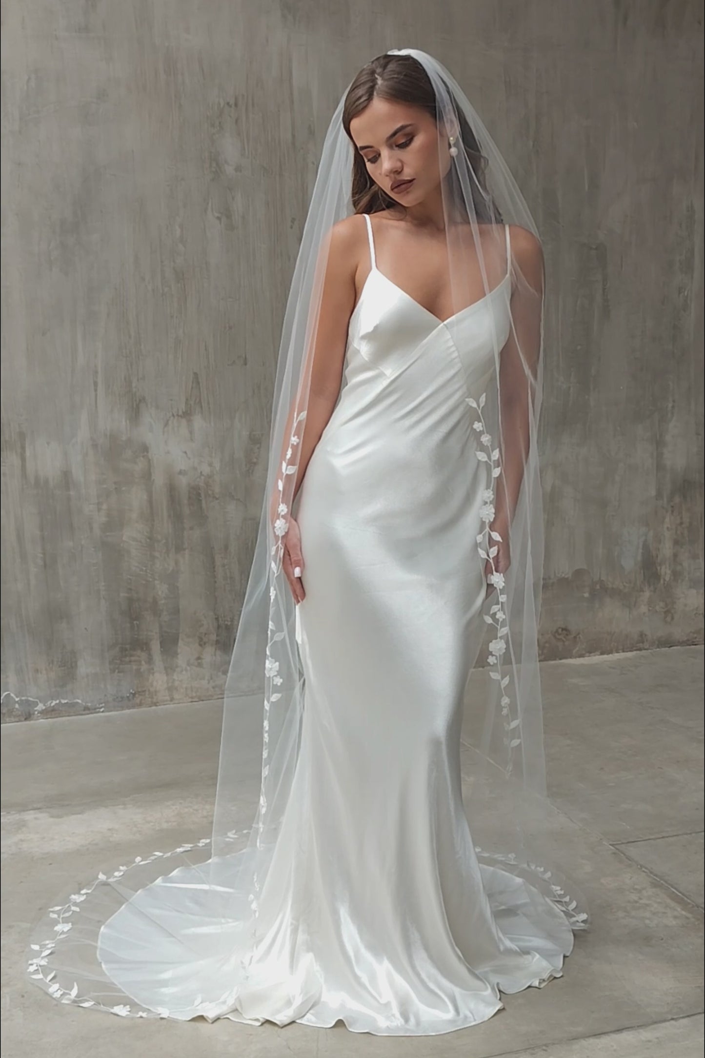Full length front facing view of bride wearing long, single tiered veil featuring delicate floral vine embroidery along the edge