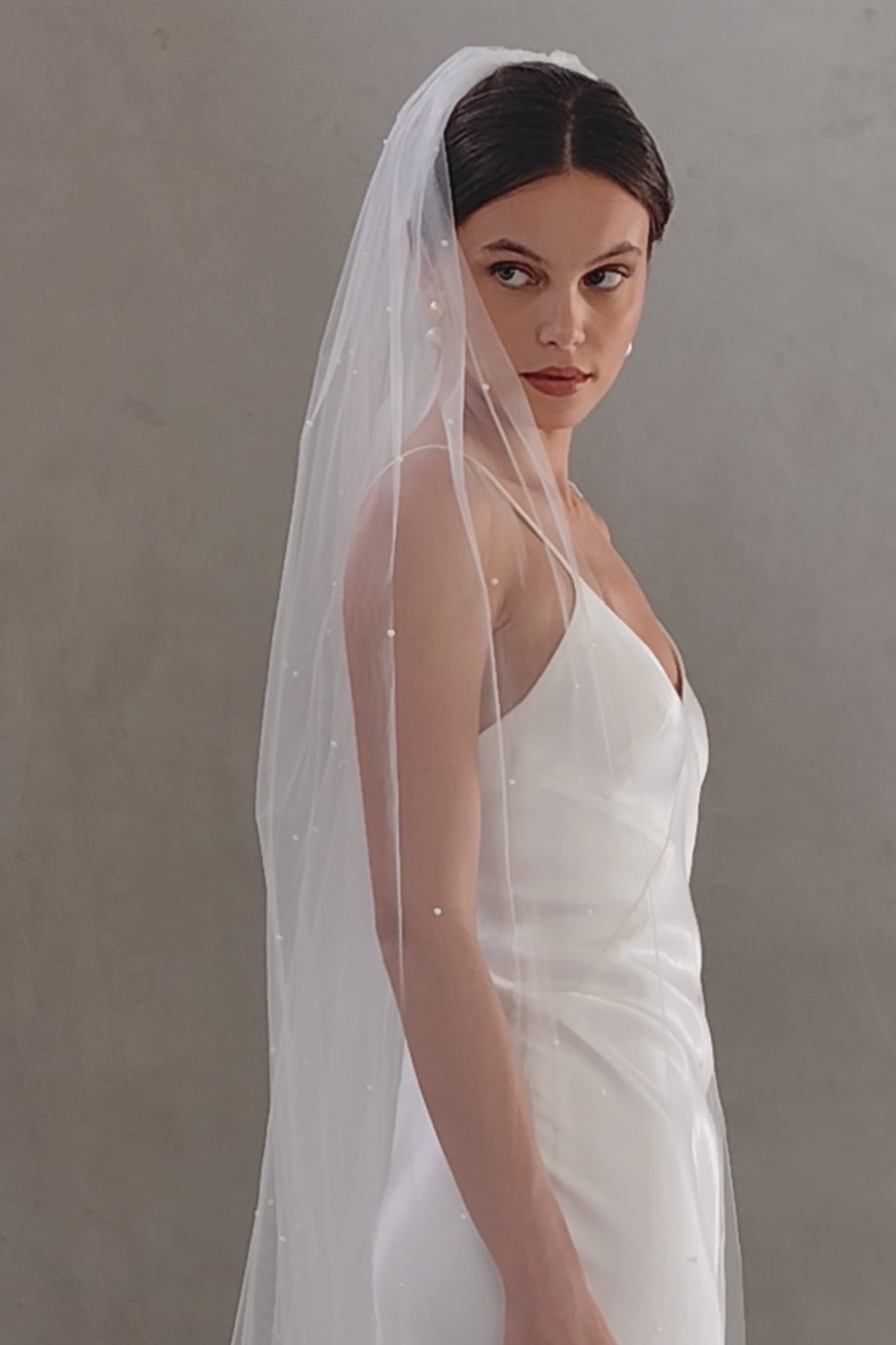 Half length view of bride wearing one tier veil scattered with tiny pearls