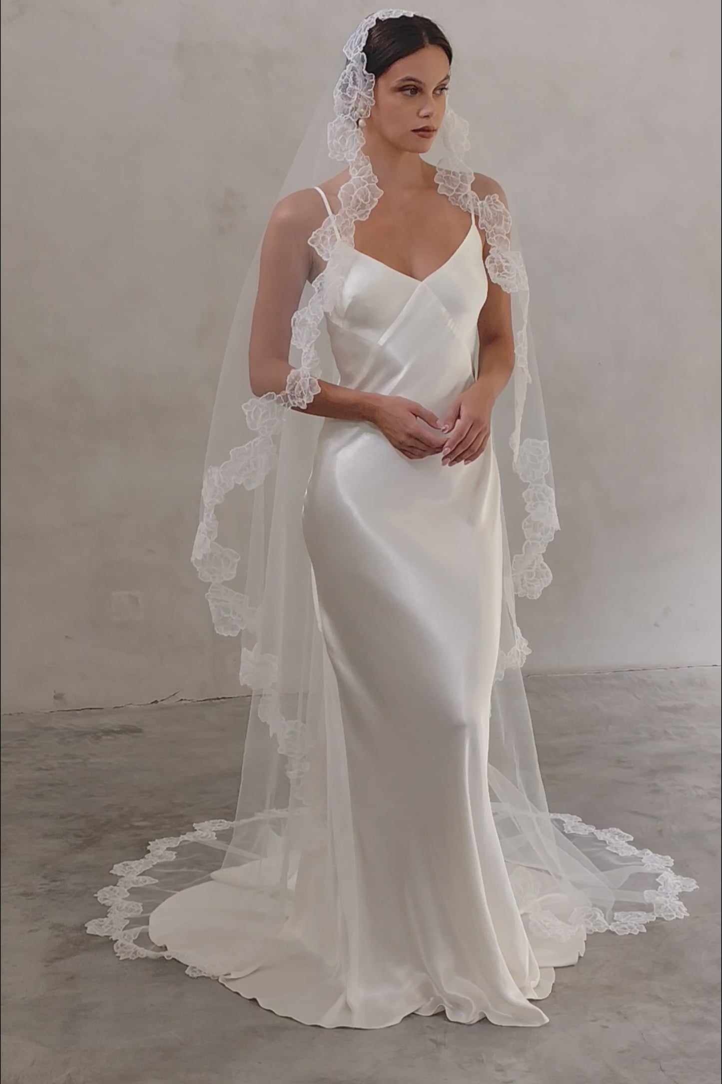 Bride wears a mantilla wedding veil with delicate floral lace