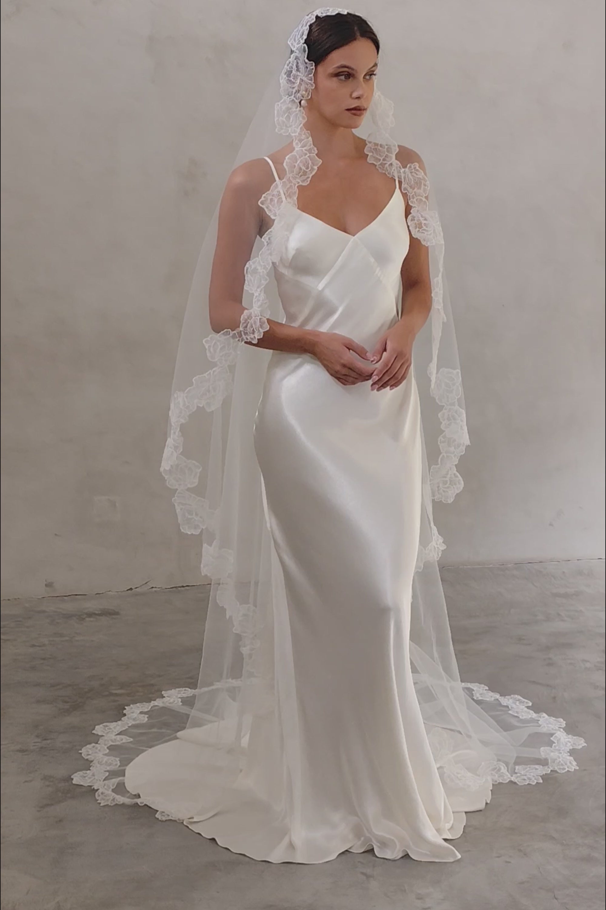 Bride wears a mantilla wedding veil with delicate floral lace