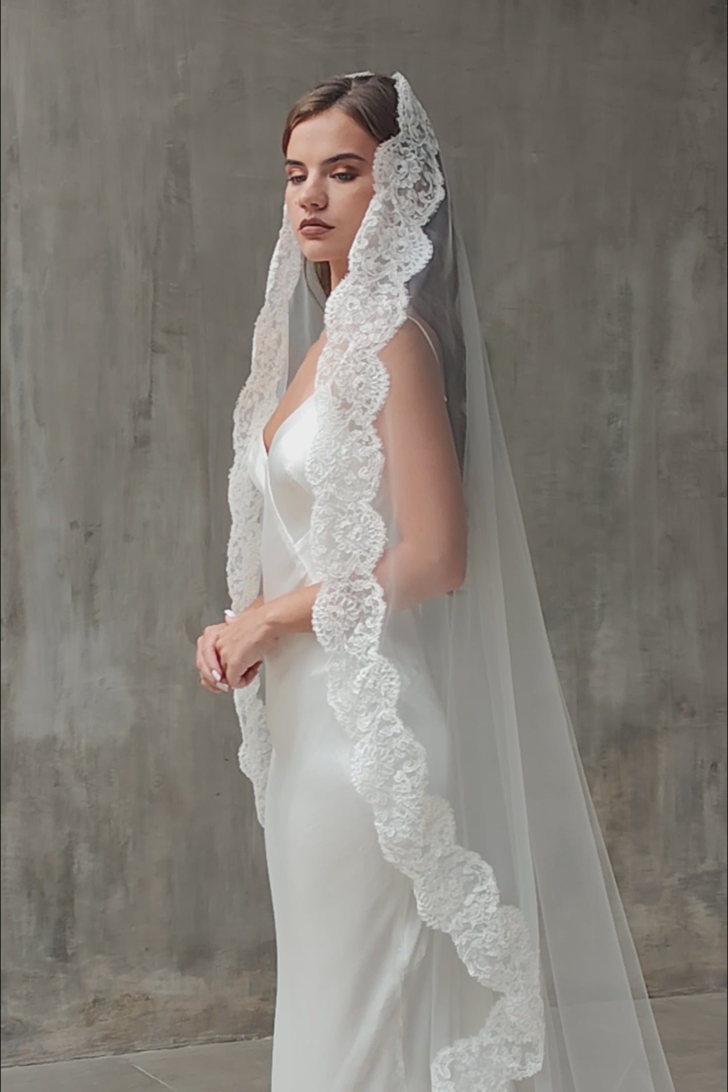Half length side view of lace trimming on long mantilla bridal veil