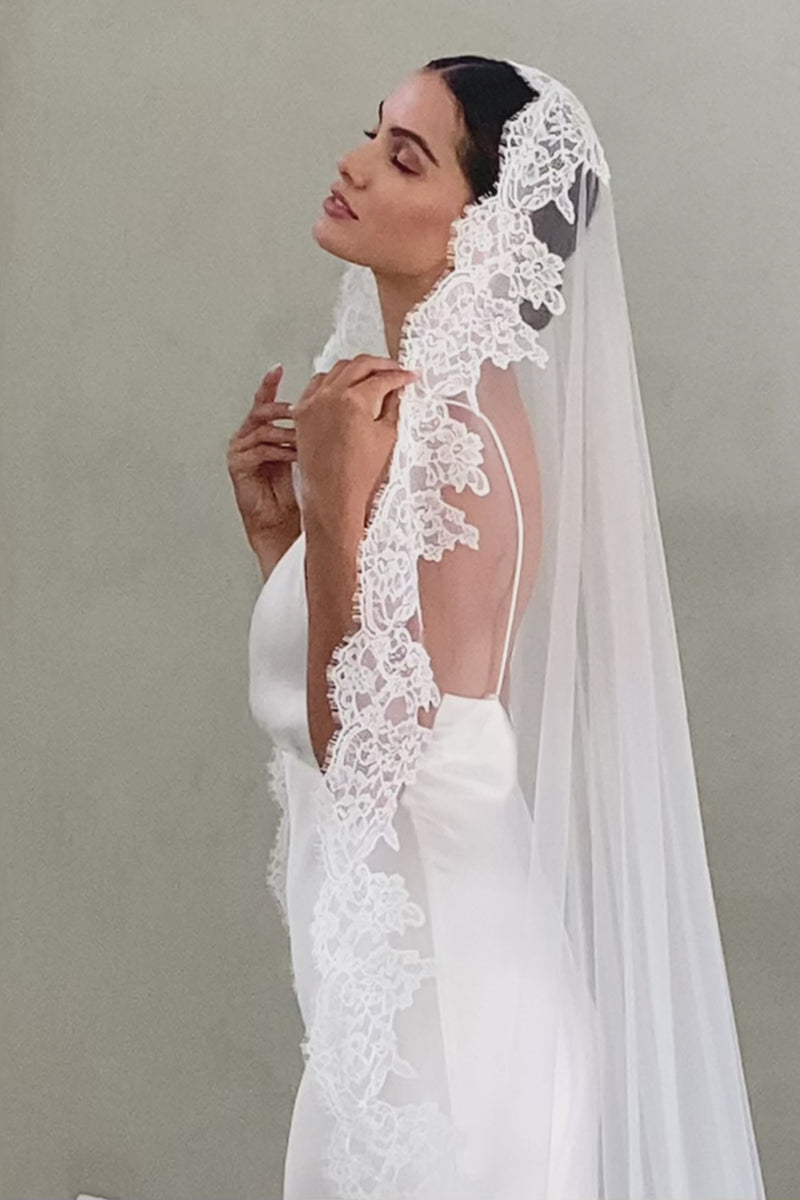 Half length side view of bride wearing long, lace edged mantilla veil