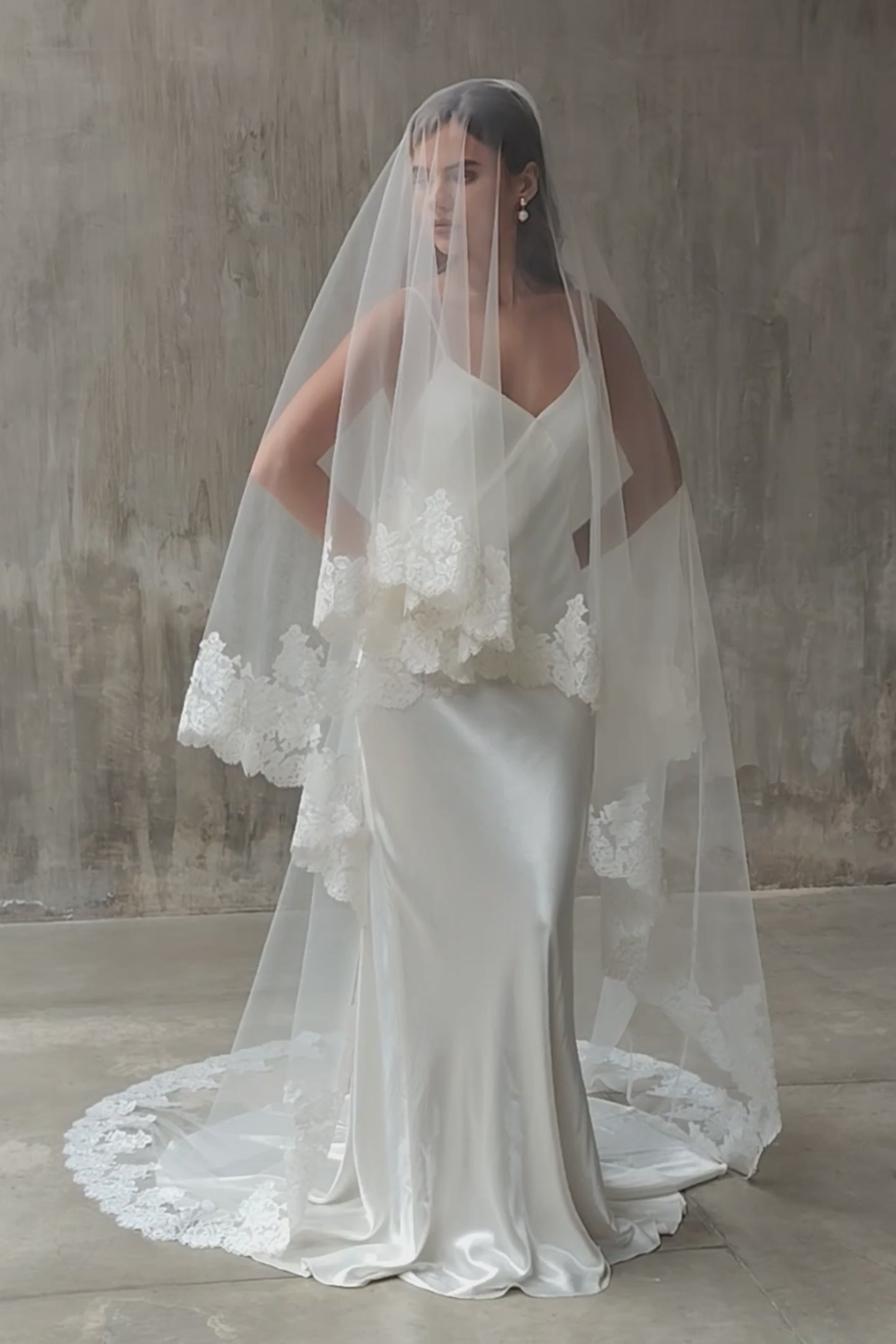 Full length front facing bride wears two tier, lace trimmed wedding veil, blusher down