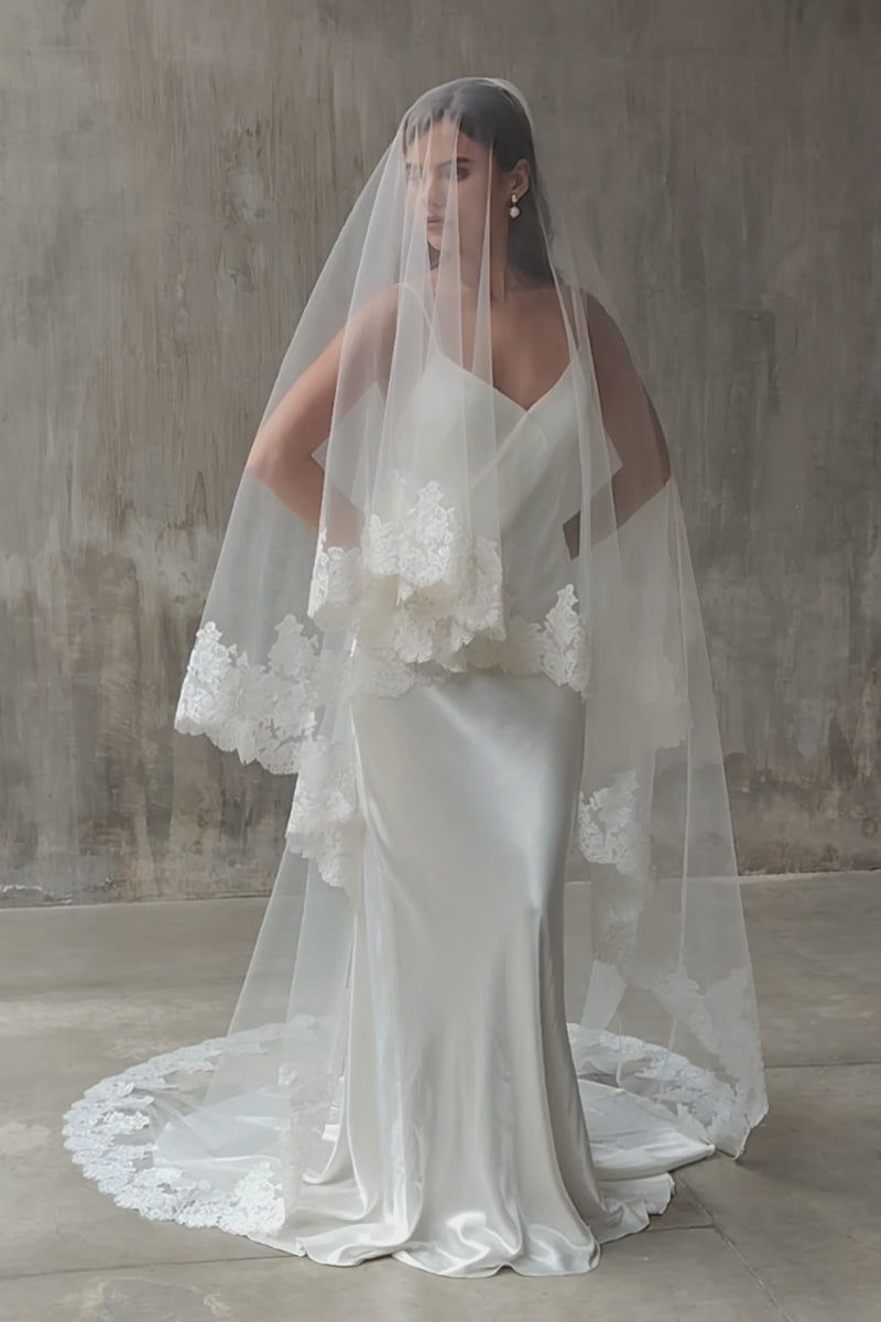 Full length front facing bride wears two tier, lace trimmed wedding veil, blusher down