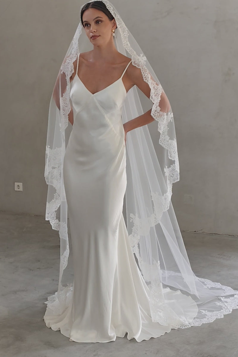 Full length front facing bride wears romantic mantilla style long veil with lace trim