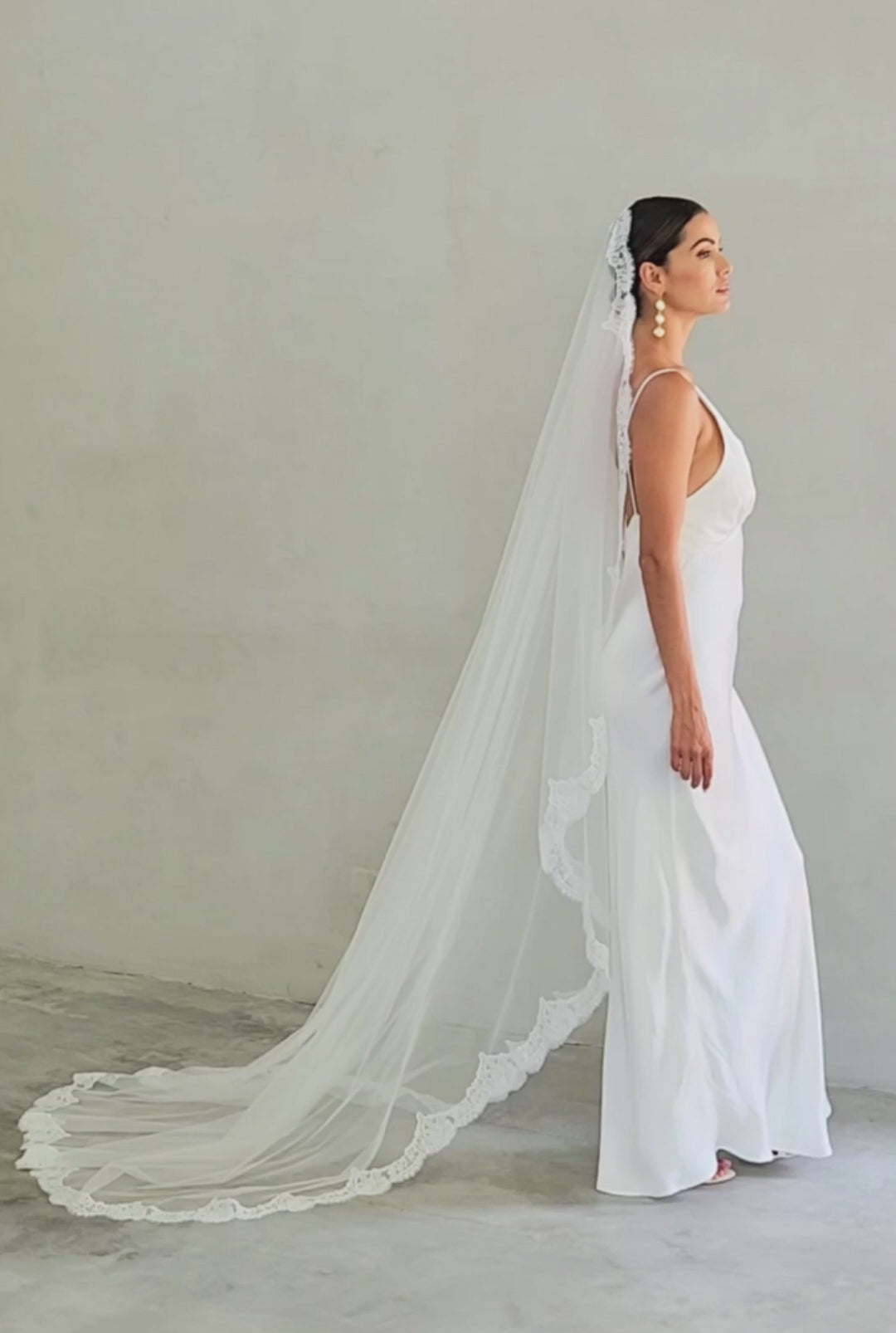 Model in side view wears long, lace edged mantilla veil by Madame Tulle