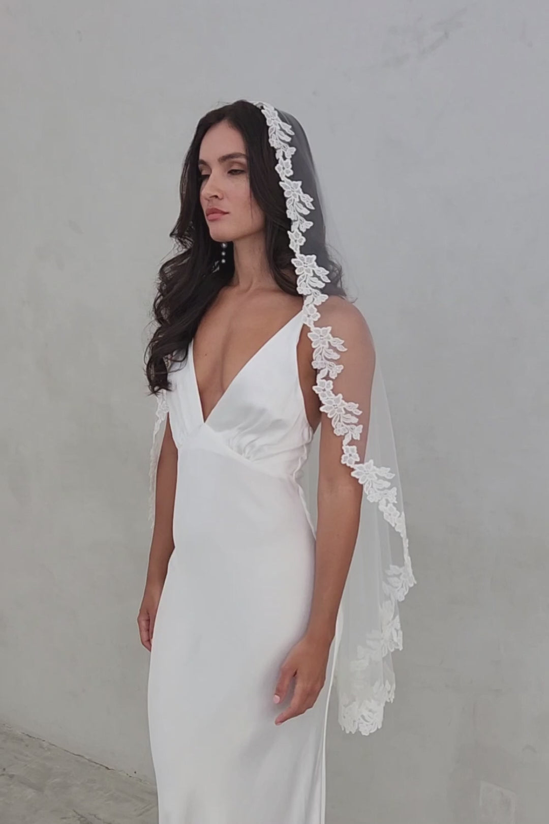 Model wears fingertip length mantilla veil trimmed with floral lace applique by Madame Tulle