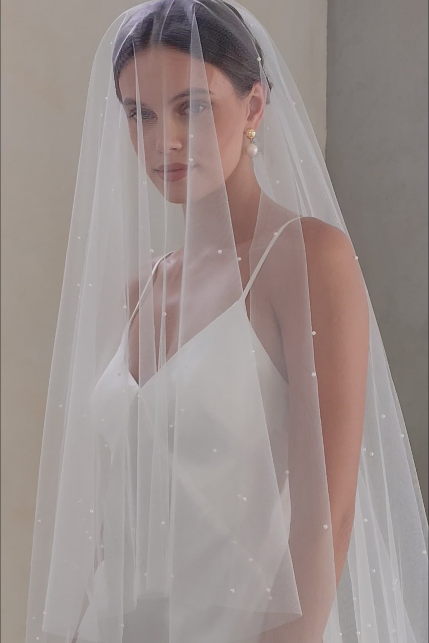 Half length front facing bride wears tulle veil with blusher and scattered with tiny pearls