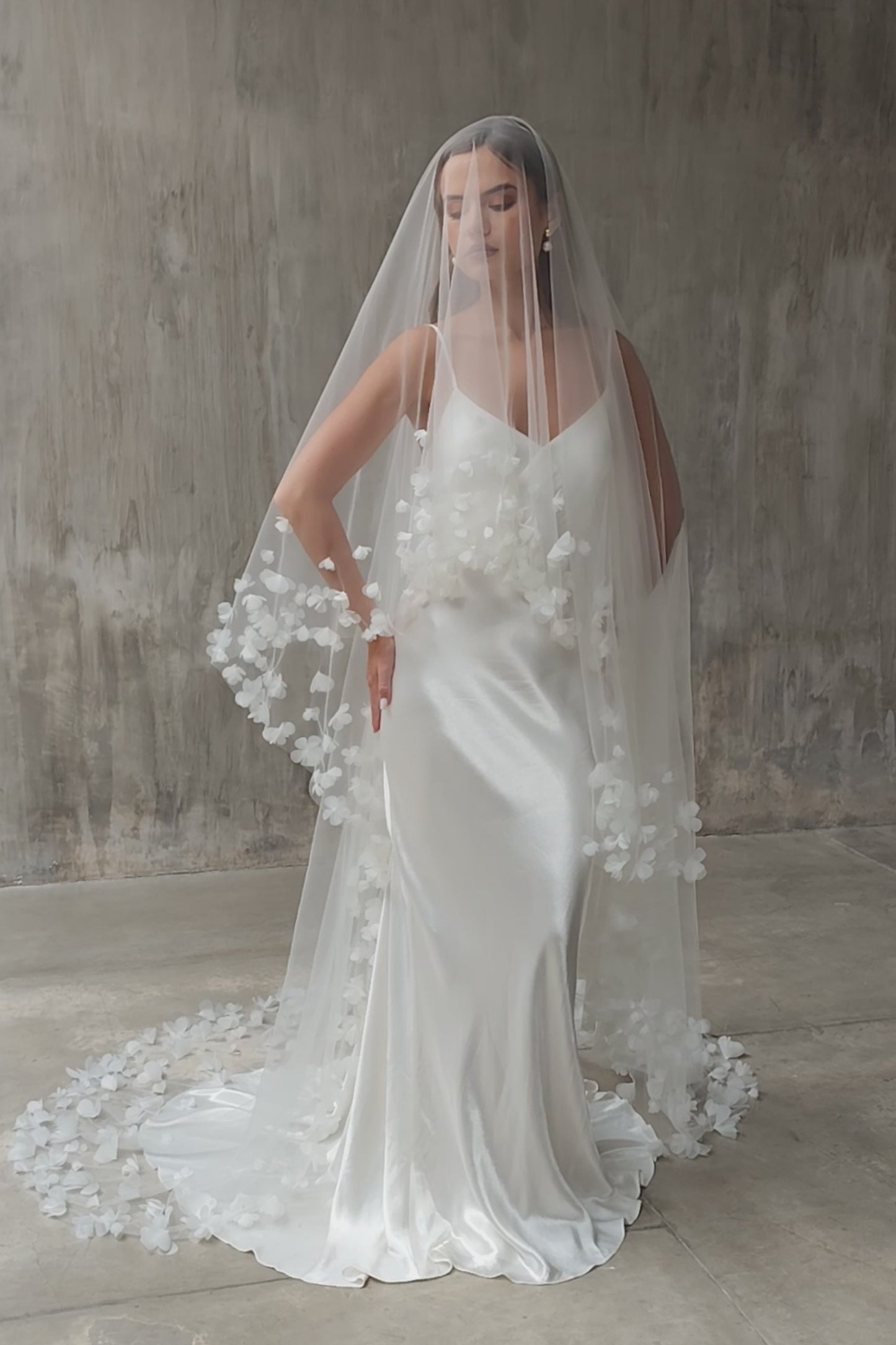 Full length front facing bride wears long veil with blusher and edged with fabric flowers