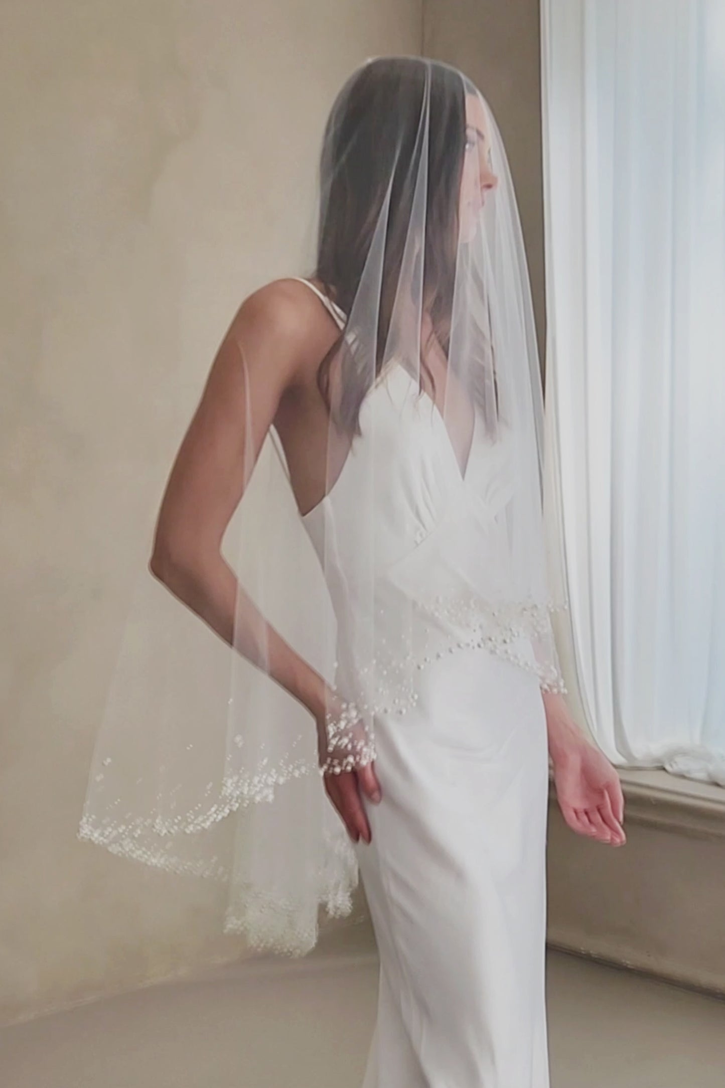 Model wears a two-tier wedding veil, drop veil with pearls and sequins