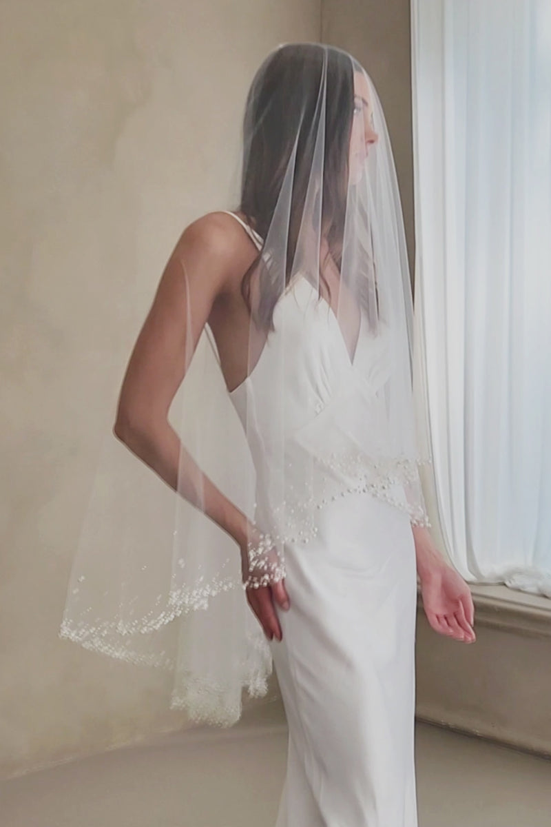 Model wears a two-tier wedding veil, drop veil with pearls and sequins