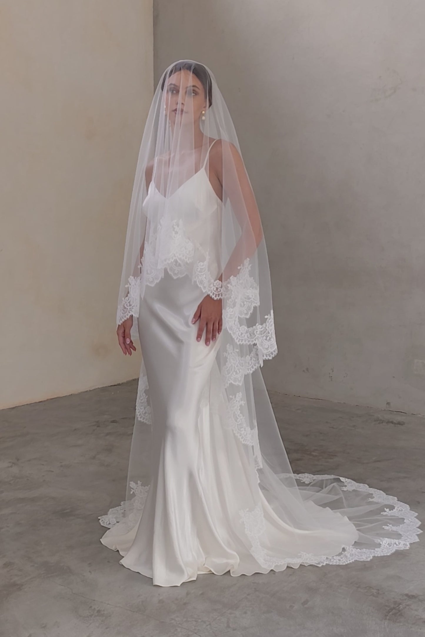 Full length front-facing bride wears long, lace-edged drop-veil; blusher down