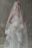 Front facing bride wears blusher down on long two tier wedding veil trimmed with corded lace trim
