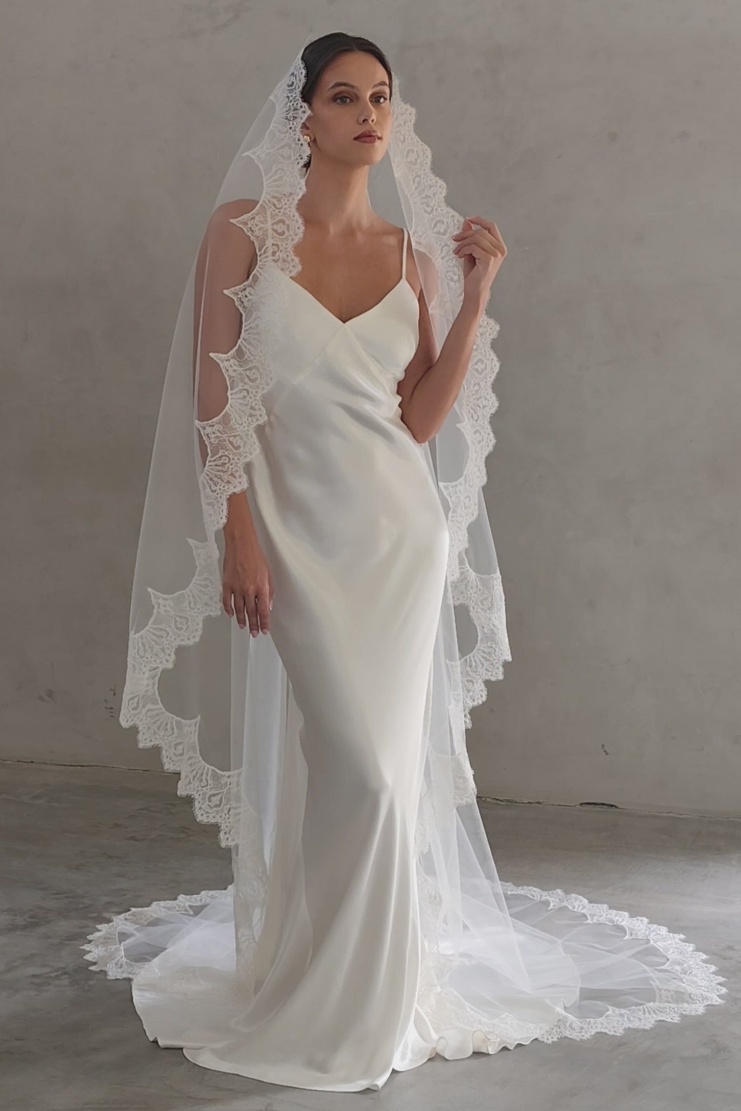 Full length front facing bride wears long, scallop lace edged mantilla style veil