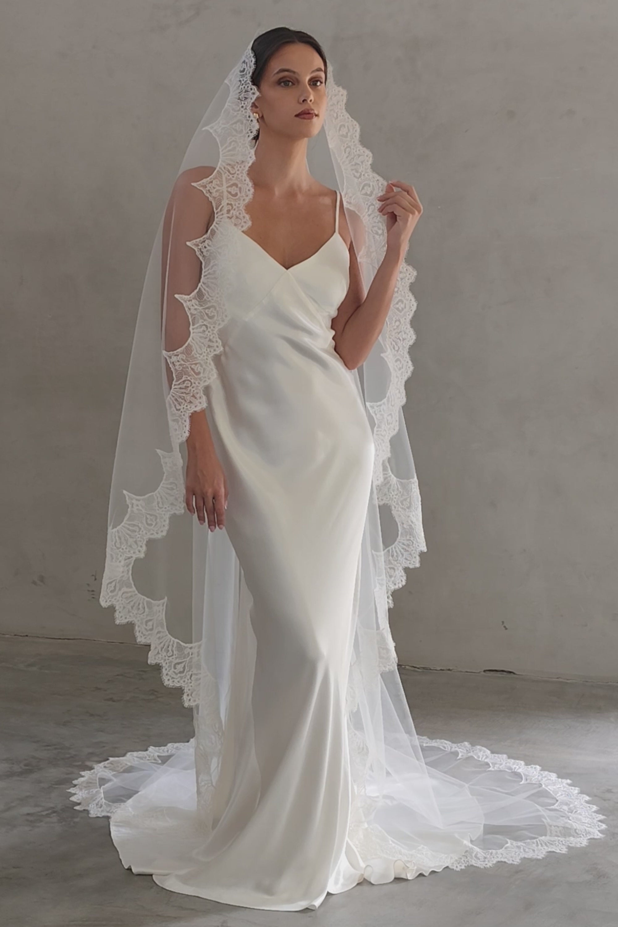 Full length front facing bride wears long, scallop lace edged mantilla style veil