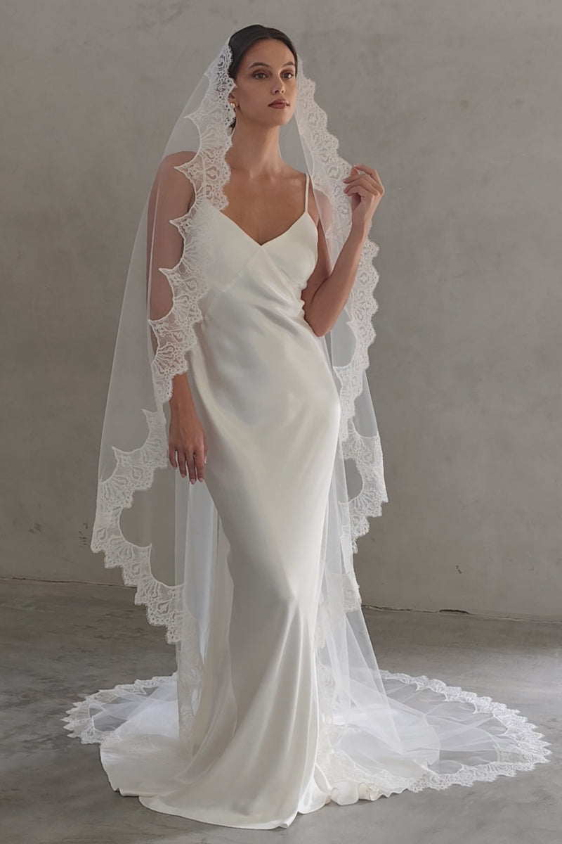 Full length front facing bride wears long, scallop lace edged mantilla style veil
