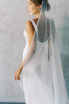 A model wearing a one tier wedding veil with pearls in chapel length