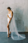 A model wearing a one tier wedding veil with pearls in chapel length