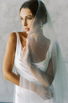 A model wearing a two tier wedding veil with pearls in chapel length