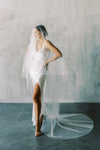 A model wearing a two tier wedding veil with pearls in chapel length