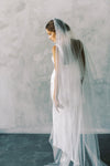 A model wearing a two tier wedding veil with pearls in chapel length