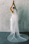 A model wearing a two tier wedding veil with pearls in chapel length