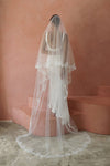 A model wearing CELINE II, a two tier lace wedding veil in cathedral length by Madame Tulle