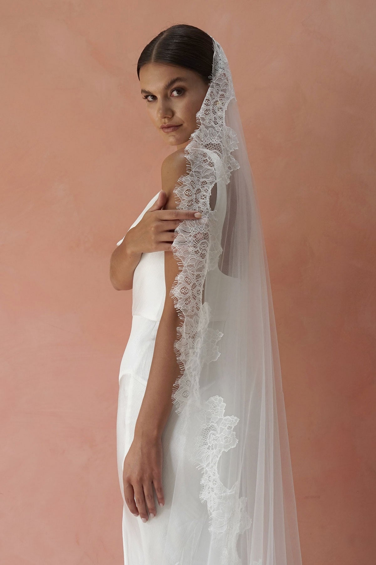 A model wearing CHANTELLE I, a lace Mantilla veil in cathedral length by Madame Tulle
