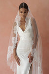 A model wearing CHANTELLE I, a lace Mantilla veil in cathedral length by Madame Tulle