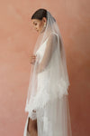 A model wearing CHANTELLE II, a two tier lace wedding veil in cathedral length by Madame Tulle