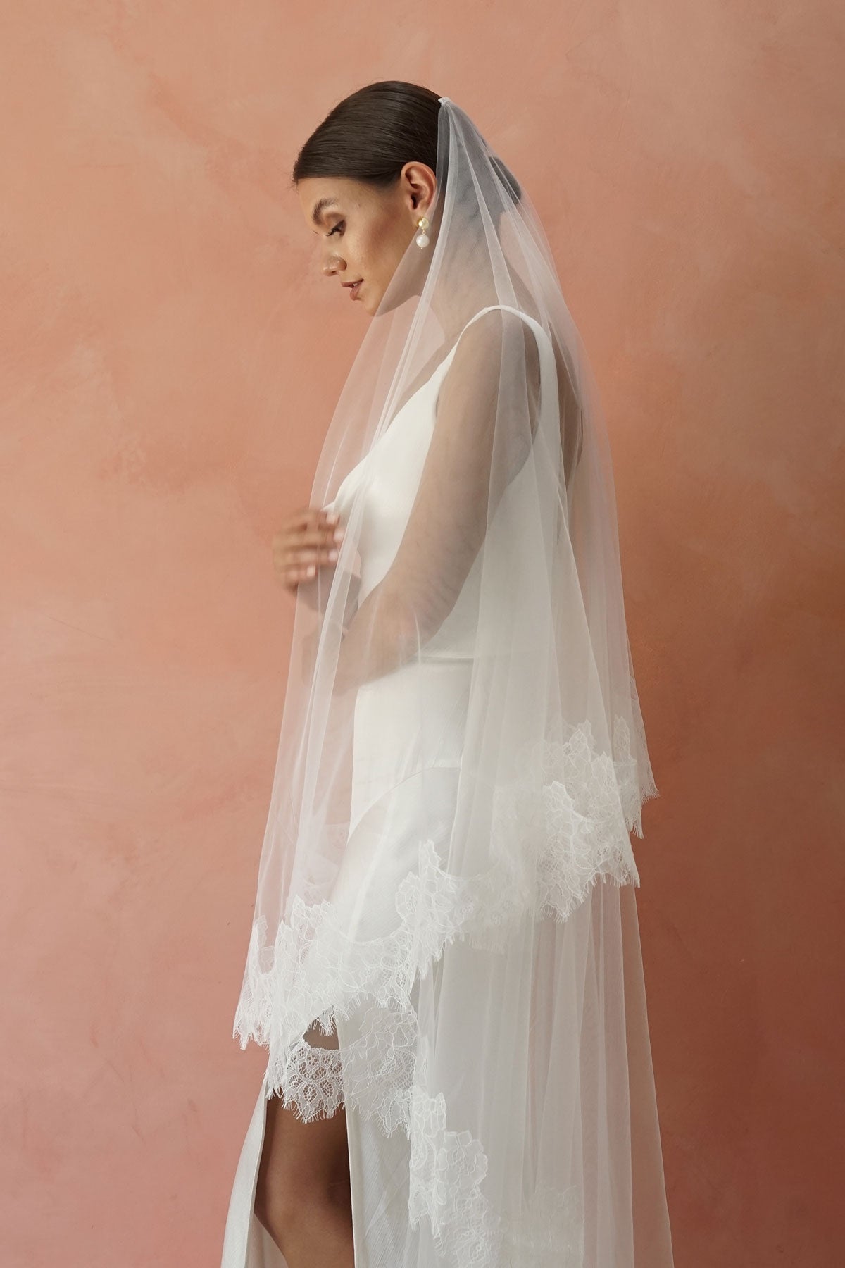 A model wearing CHANTELLE II, a two tier lace wedding veil in cathedral length by Madame Tulle