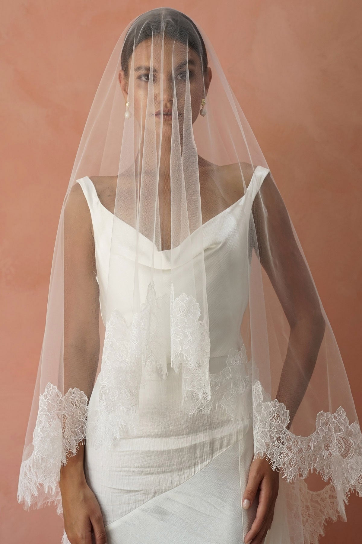 A model wearing CHANTELLE II, a two tier lace wedding veil in cathedral length by Madame Tulle