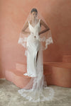 A model wearing CHANTELLE II, a two tier lace wedding veil in cathedral length by Madame Tulle