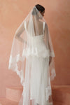 A model wearing CHANTELLE II, a two tier lace wedding veil in cathedral length by Madame Tulle