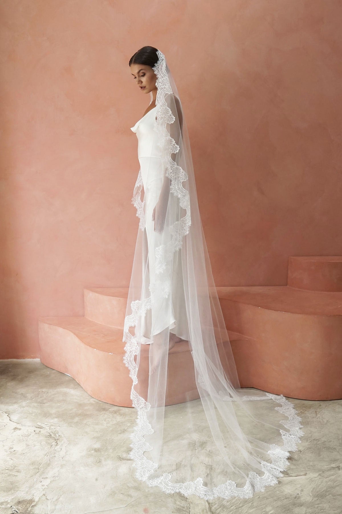 A model wearing COLETTE I, a lace Mantilla one tier veil