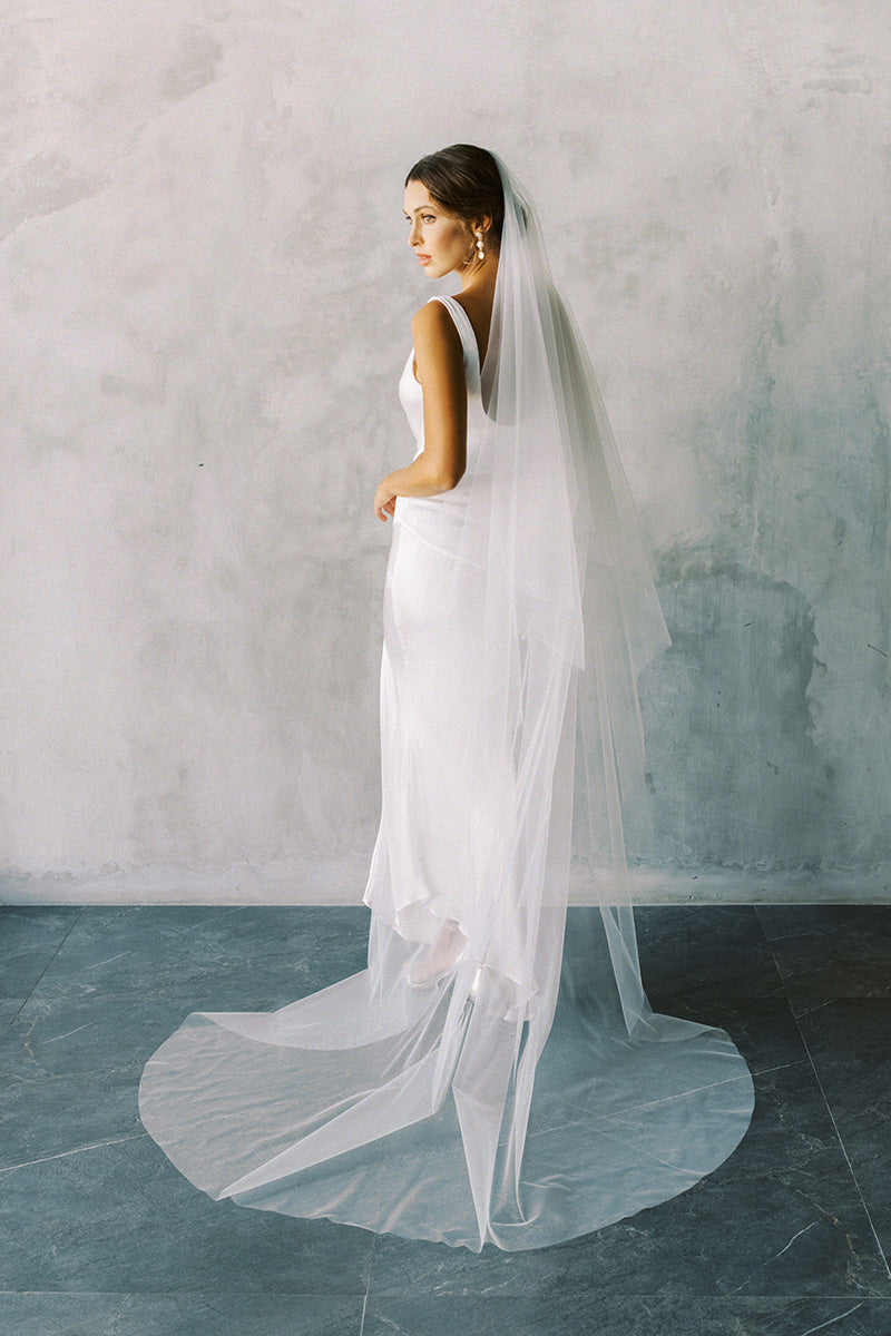 A model wearing the ELLA II drop veil in chapel length, ivory colour.