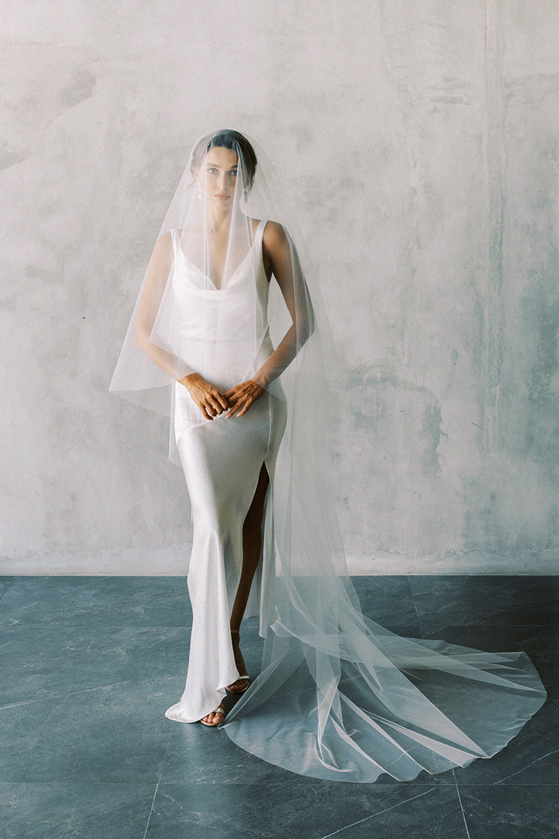 A model wearing the ELLA II drop veil in chapel length, ivory colour.