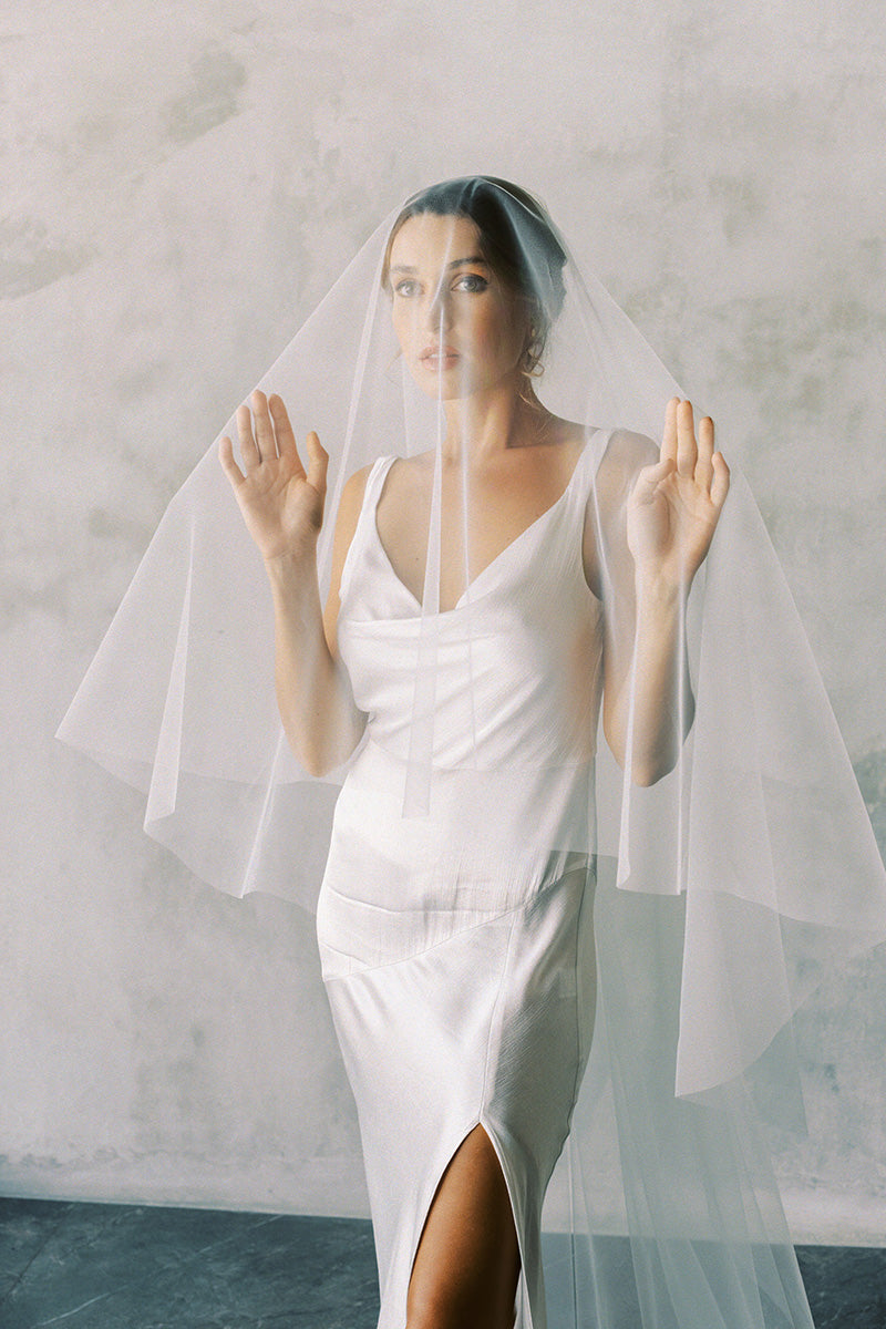 A model wearing the ELLA II drop veil in chapel length, ivory colour.
