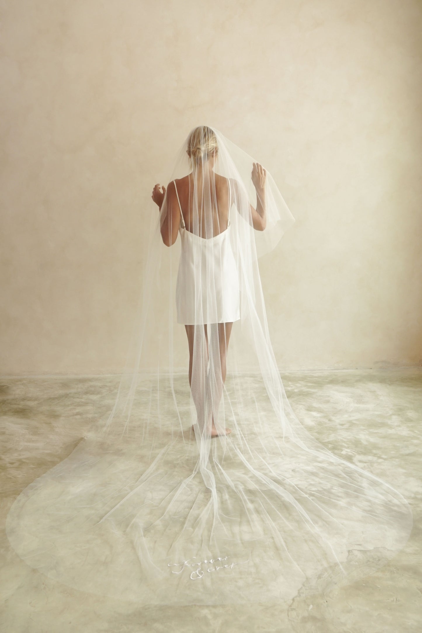 A model wearing a long one tier veil with embroidered text forever and ever