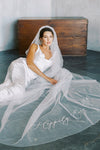 A model wearing embroidered wedding veil in cathedral length with text happily ever after