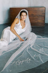 A model wearing embroidered wedding veil with text happily ever after