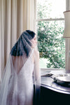 A model wearing MARIBEL I one tier pearl wedding veil by Madame Tulle