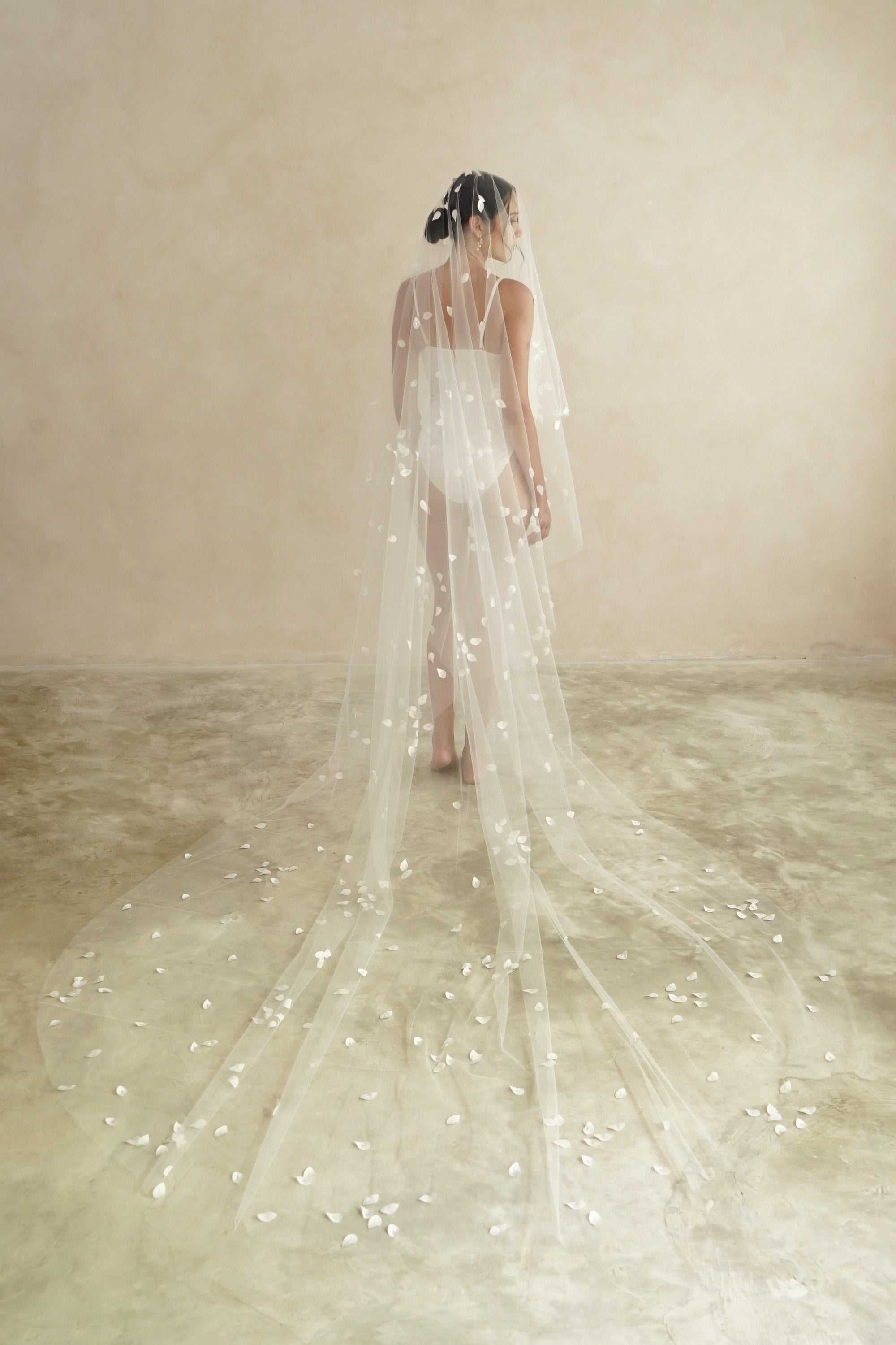model wears a two-tier petal veil, drop veil with satin petal and glass beads