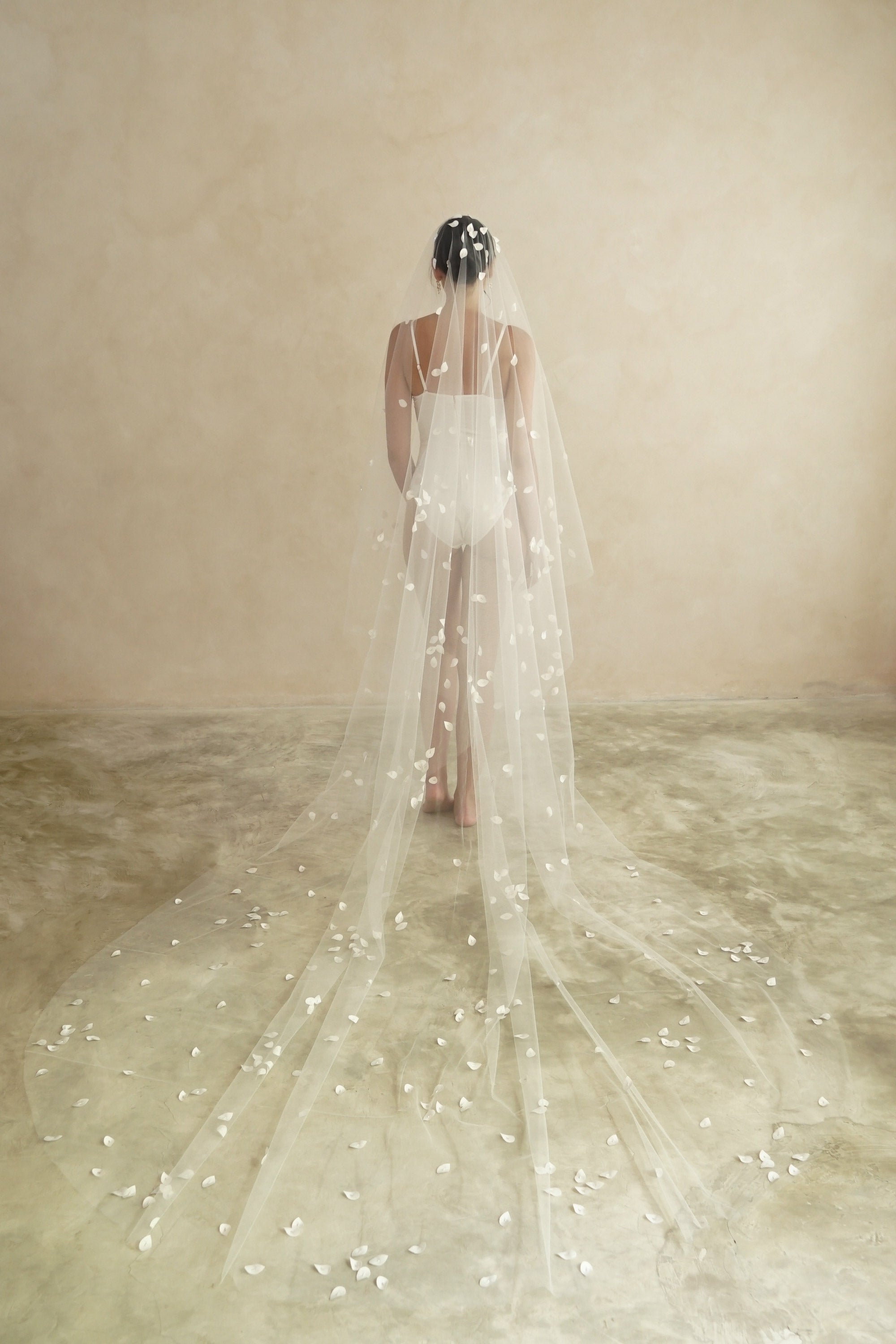 model wears a two-tier petal veil, drop veil with satin petal and glass beads