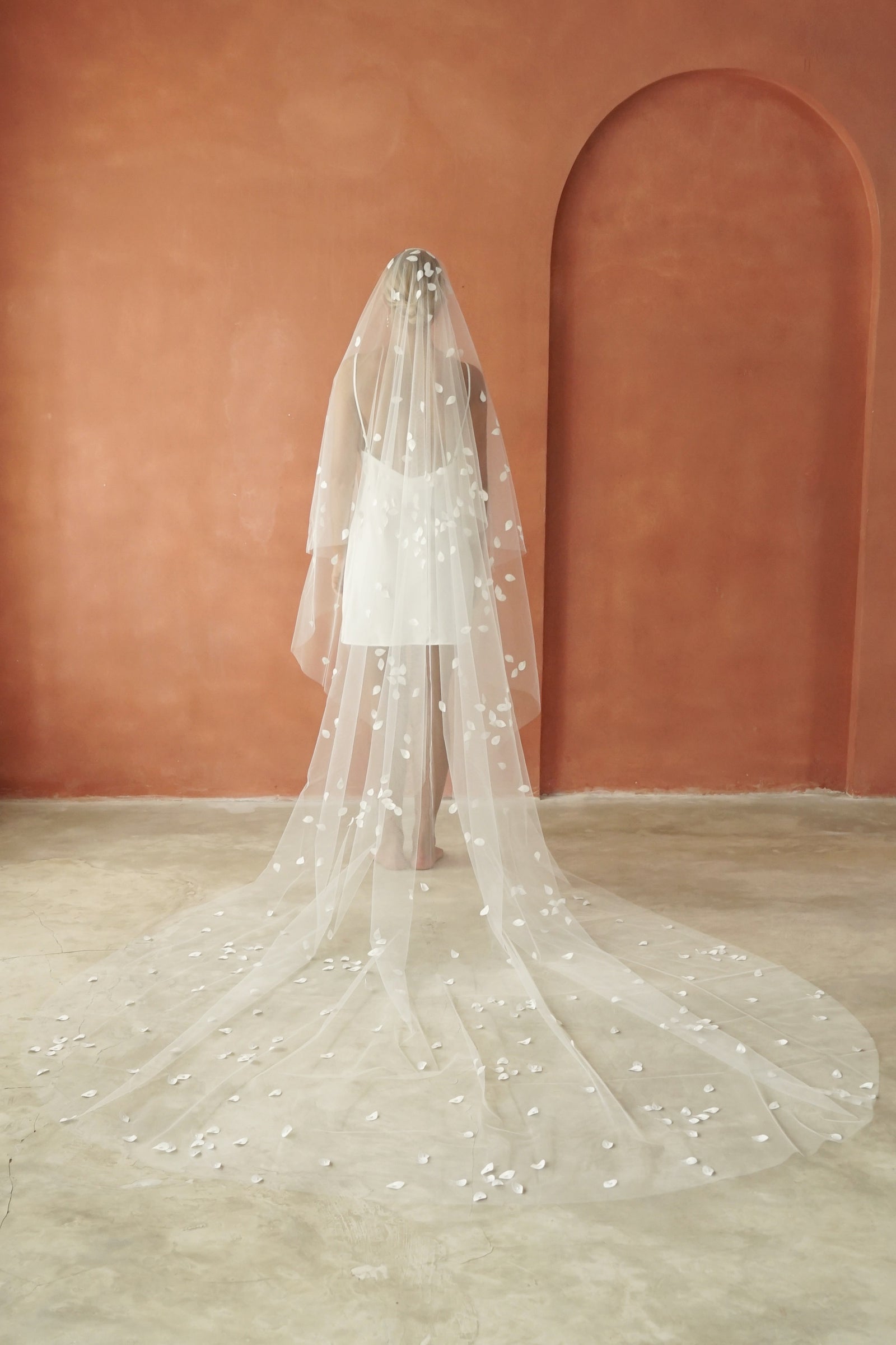 model wears a two-tier petal veil, drop veil with satin petal and glass beads