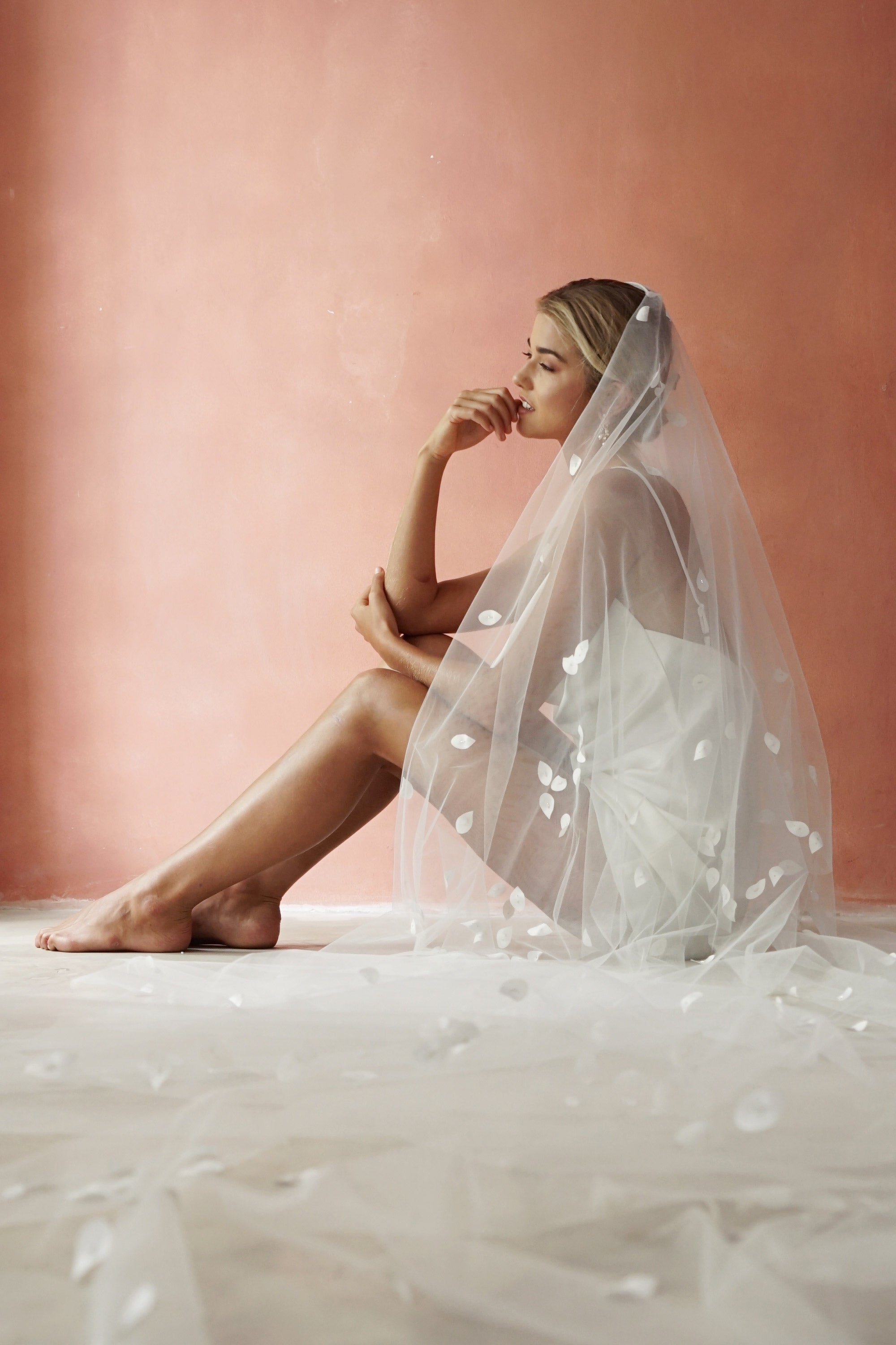 model wears a two-tier petal veil, drop veil with satin petal and glass beads