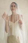 A model wearing a two tier wedding veil with large pearls by Madame Tulle