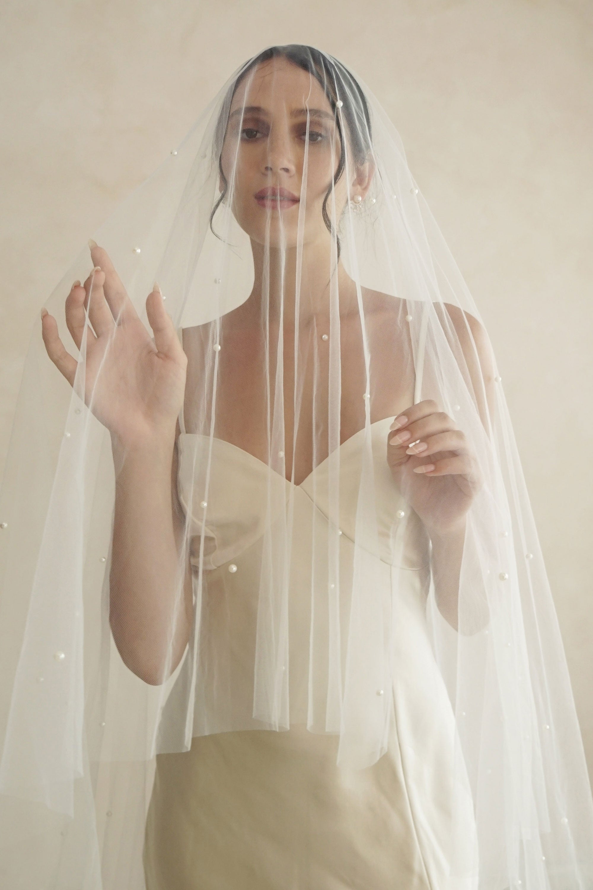A model wearing a two tier veil with large pearls by Madame Tulle